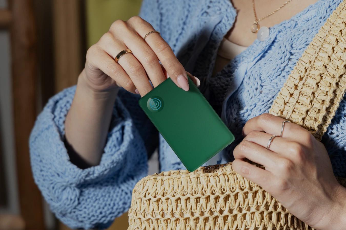A Life360 Tile Slim - Green Surf being placed inside of a handbag.