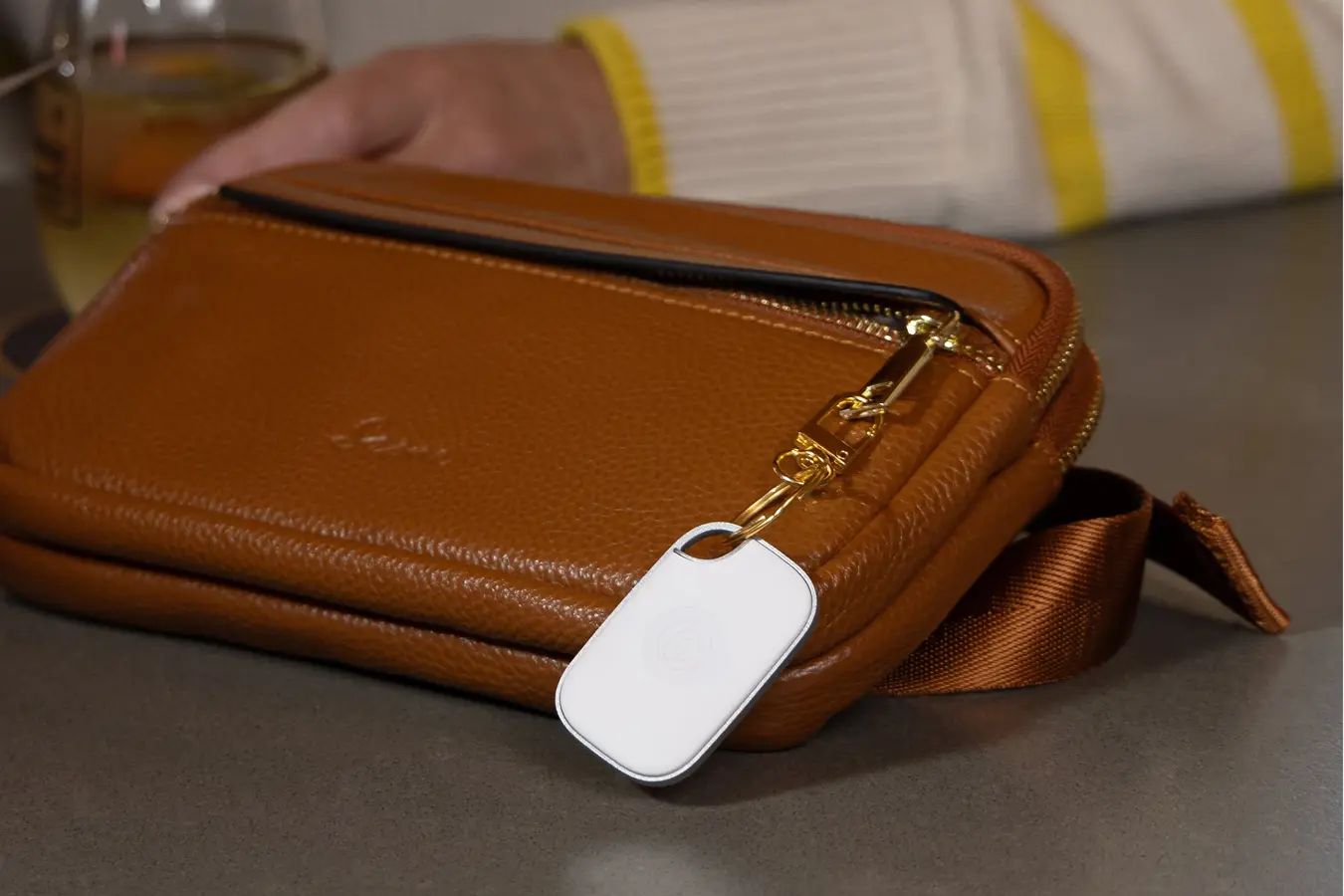 Image of a Tile Pro- White attached to a tan bag