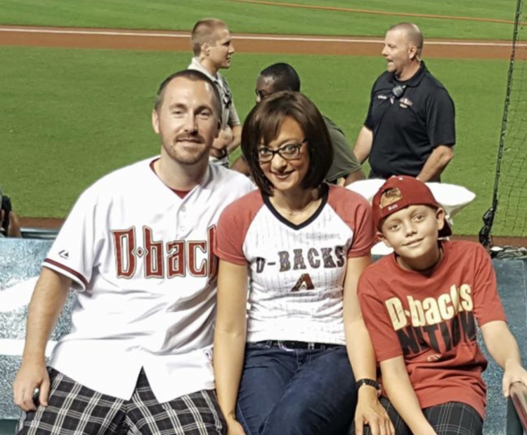 A family of three posing for a picture at an Arizona Diamondbacks game