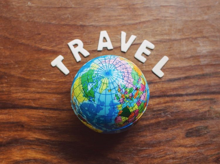 A globe on a table with letters spelling out "travel" over it