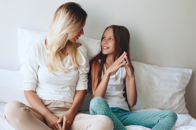 Mother and daughter talking on a bed
