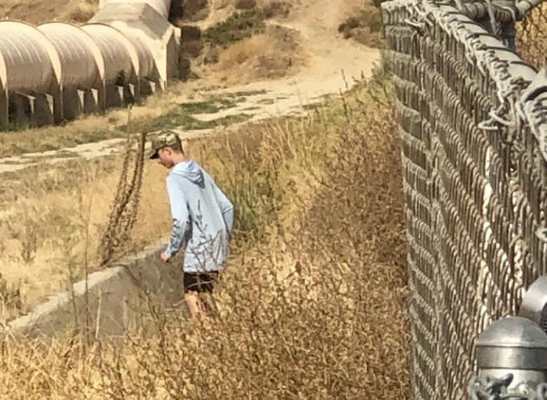 Person near a fence in a desert field