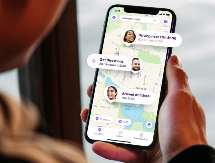 Woman holding phone with Life360 app open with notifications from Circle members