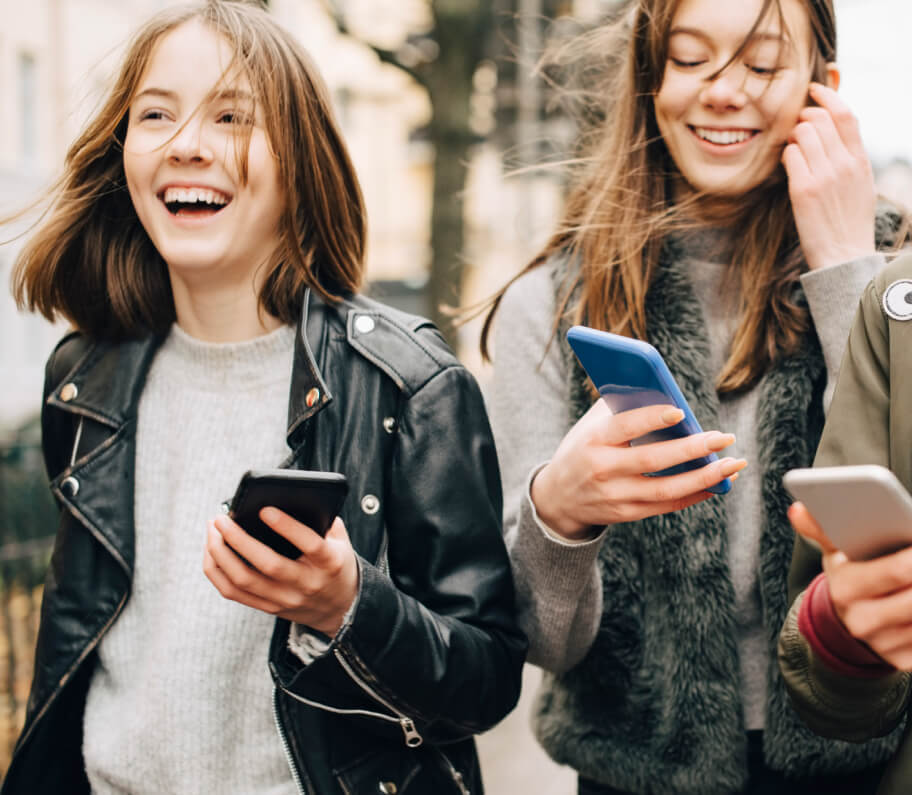 Teenagers walking and laughing with cellphones in their hands