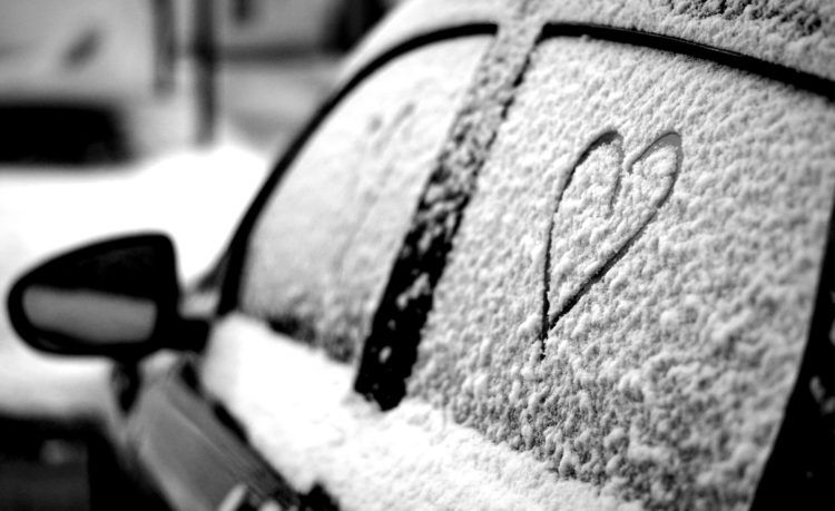 Black snow-covered car with heart draw on rear window