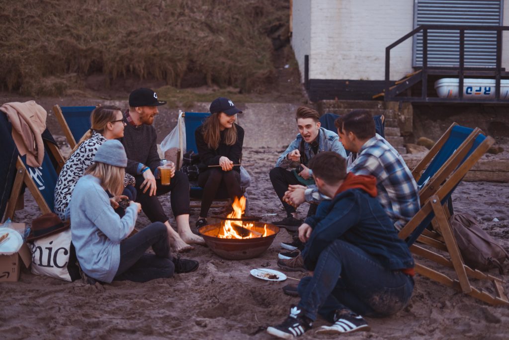 Group of seven young adults hanging out around a campfire