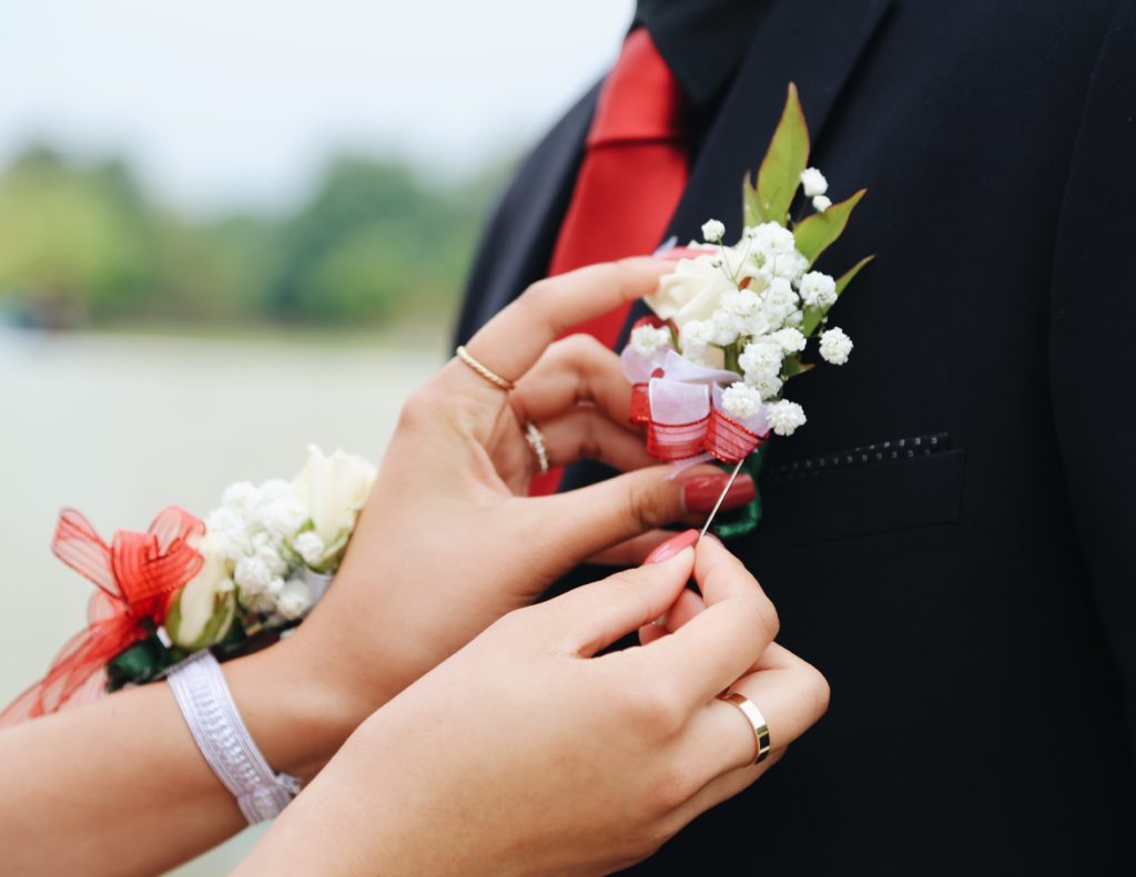 Girl putting a corsage on her prom dates lapel