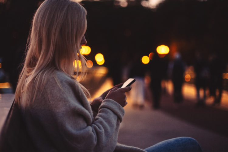 Young teen girl looking down at her phone an night